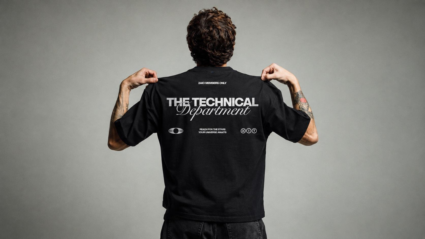 Model holding up the back of a black Zaio tee printed with The Technical Department
